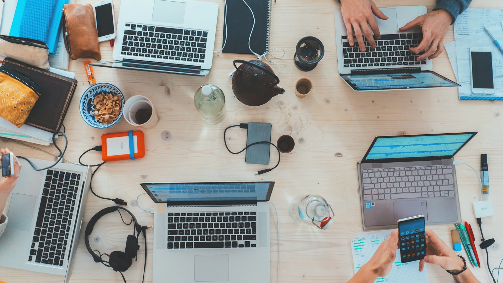 An overhead view of a team working at laptops around a table with coffee