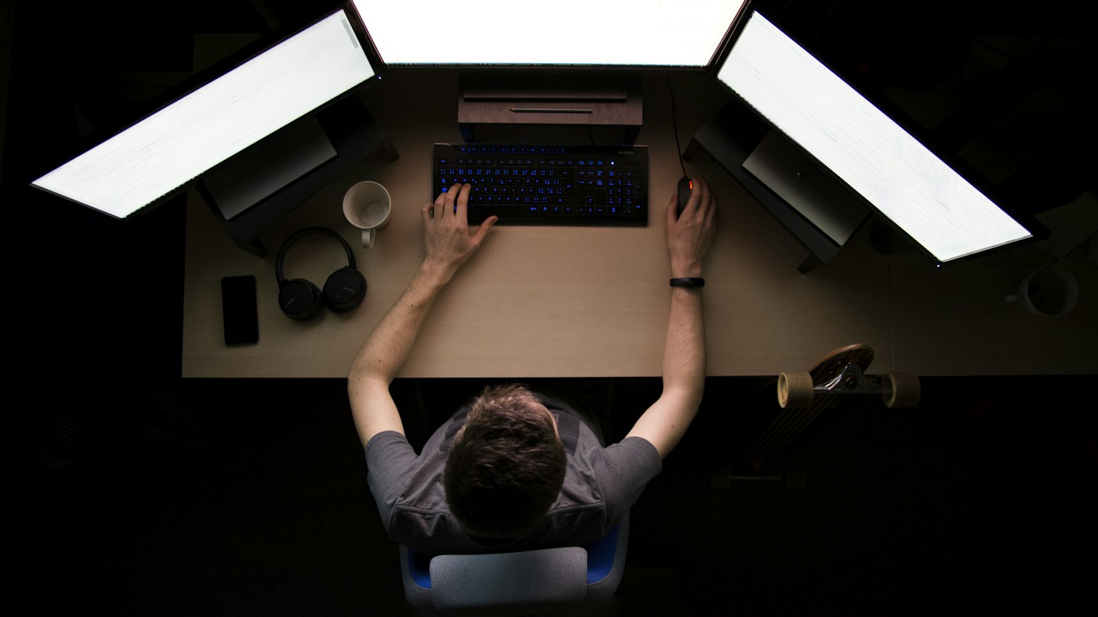 An overhead view of a developer working at a laptop under dramatic lighting