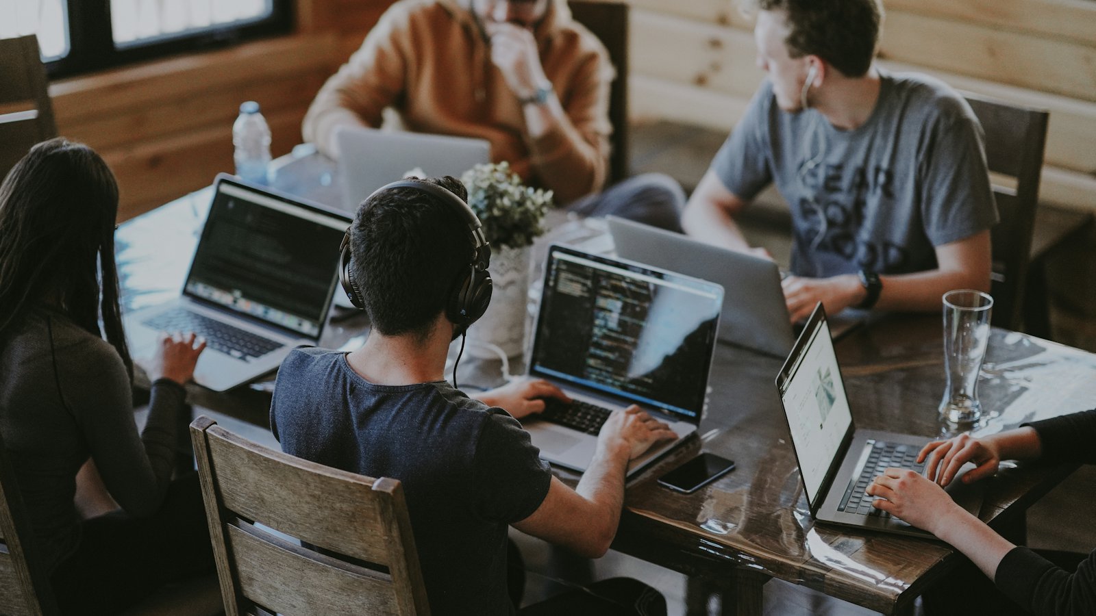 A small team meeting around a table with laptops open
